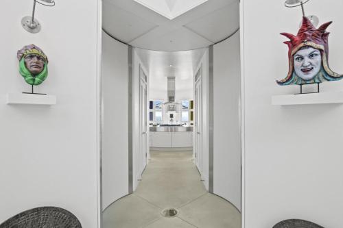 A modern hallway with colorful masks on the walls, leading to a bright kitchen area.