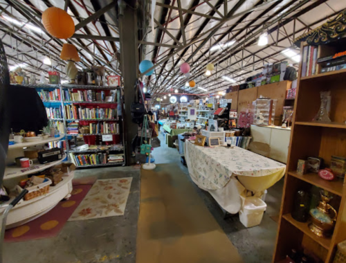 A spacious indoor market with bookshelves, tables, and colorful lanterns hanging from the ceiling.