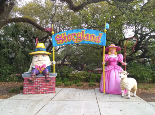 Colorful entrance to Storyland featuring a large Humpty Dumpty and a princess with a sheep. Lush trees in the background.