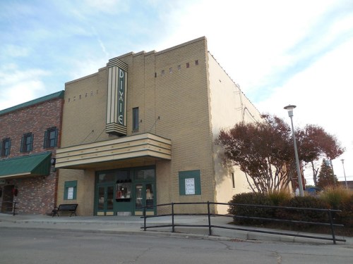 Art Deco-style theater building with a marquee, featuring a brick facade and surrounding landscaping.