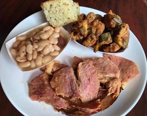 A plate featuring sliced ham, white beans, fried okra, and a piece of cornbread.