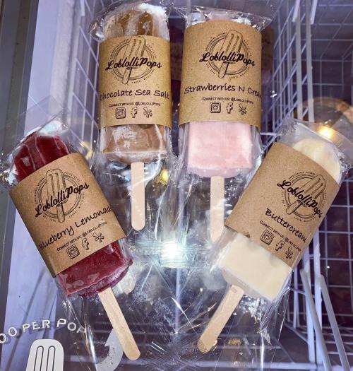 Three colorful popsicles in clear packaging: Blueberry Lemonade, Chocolate Sea Salt, and Strawberries N Cream.