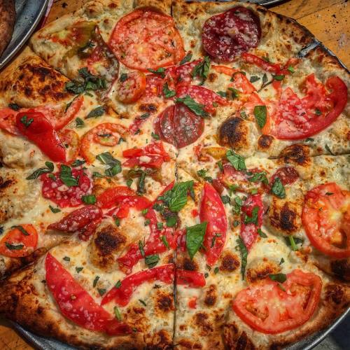 A freshly baked pizza topped with tomatoes, cheese, and fresh basil on a golden crust.