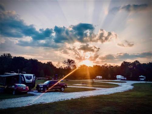 Sunset over a campground with vehicles parked along a winding gravel path and trees in the background.