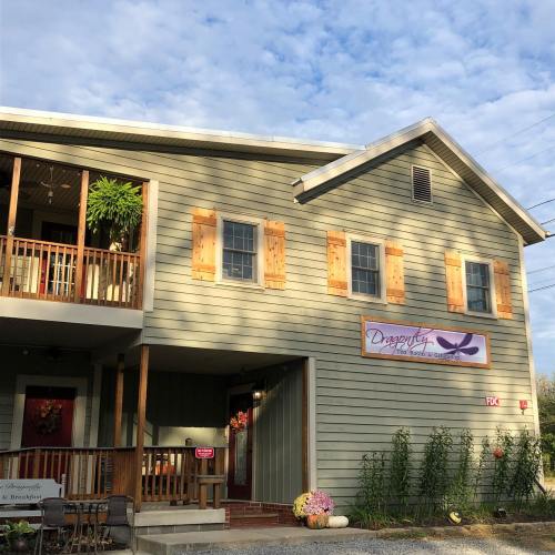 A charming two-story building with wooden shutters, a sign reading "Dragonfly," and a welcoming porch.