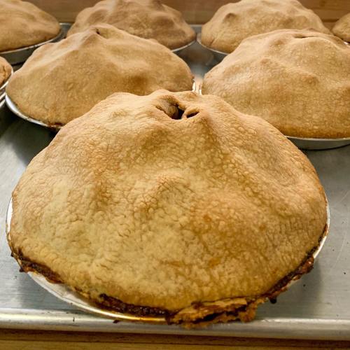 Freshly baked pies with golden, textured crusts cooling on a tray.