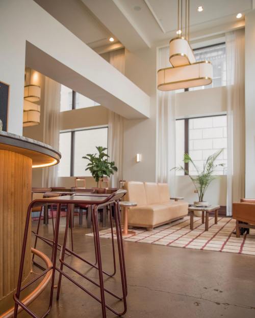 Modern lounge area with stylish seating, large windows, and decorative lighting. Warm tones and plants create a cozy atmosphere.