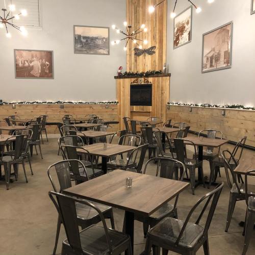 A cozy restaurant interior with metal tables and chairs, wooden accents, and vintage photos on the walls.