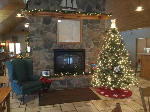 Cozy interior with a stone fireplace, decorated Christmas tree, and festive lights in a warm, inviting setting.