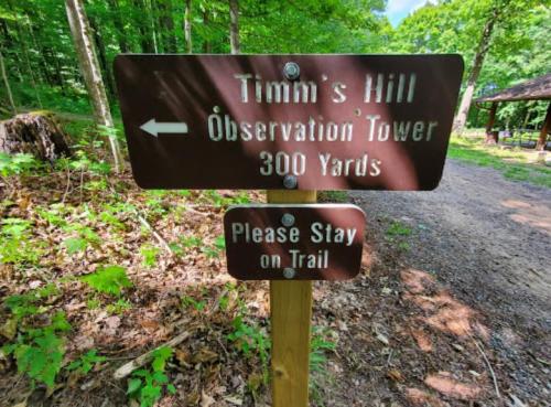 Signpost directing to Tim's Hill Observation Tower, 300 yards ahead, with a reminder to stay on the trail.