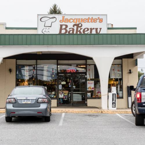 Exterior of Jacquette's Bakery with an "Open" sign, featuring parked cars in front and a welcoming storefront.