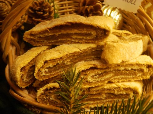 A basket filled with sliced, golden-brown pastries, surrounded by pinecones and greenery.