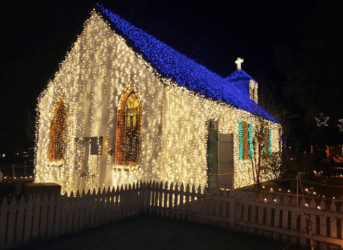 A charming church adorned with colorful holiday lights, glowing brightly against a dark night sky.