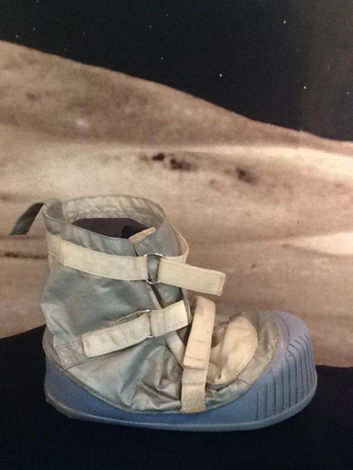 A futuristic boot with straps, set against a lunar landscape background.