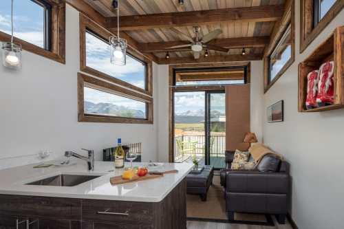 Cozy interior with a kitchen, living area, and large windows showcasing mountain views. Modern decor and natural light.