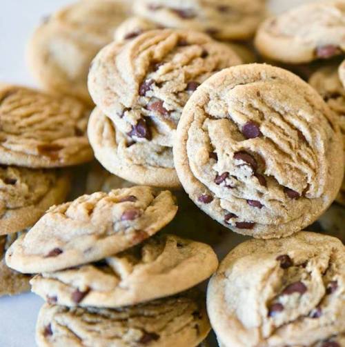 A close-up of freshly baked chocolate chip cookies stacked on a plate.