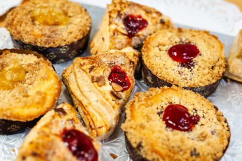 A variety of baked pastries, including fruit-filled tarts and crumb-topped treats, arranged on a silver platter.