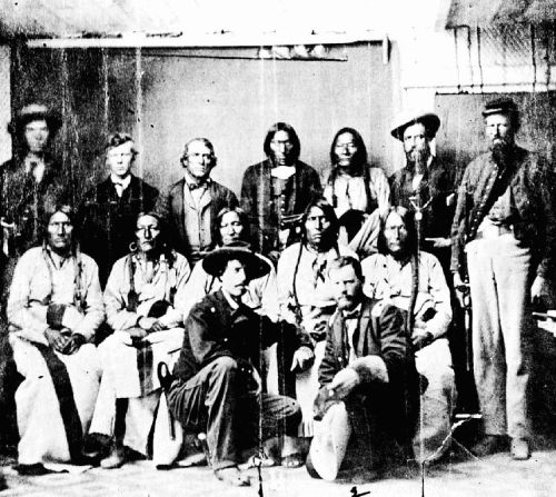 A historical black-and-white photo of a group of men, some seated and others standing, in traditional attire.