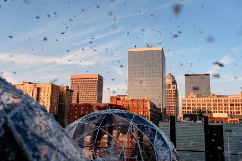 City skyline at sunset with water splashes in the foreground, showcasing modern buildings and a clear sky.
