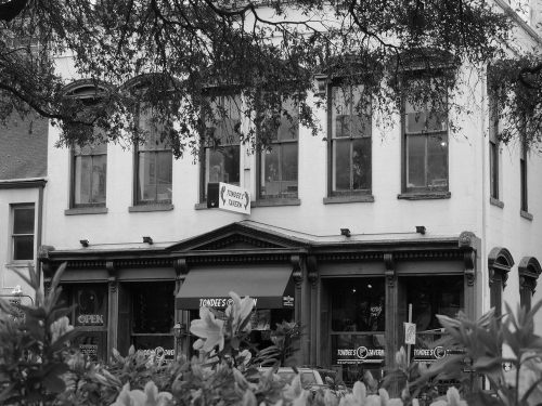 A historic building with large windows and a sign reading "Tondee's Tavern," surrounded by greenery.