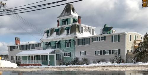 Historic building with a distinctive tower, covered in snow, surrounded by winter scenery and power lines.