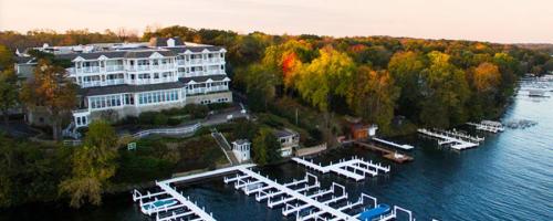 Aerial view of a lakeside hotel surrounded by colorful trees and docks on the water.