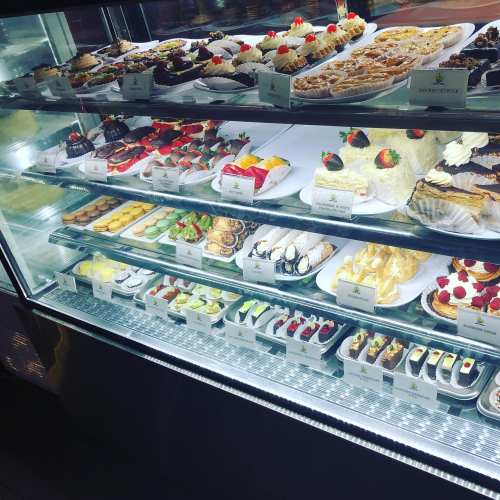 A display case filled with an assortment of colorful pastries, cakes, and desserts, beautifully arranged on plates.