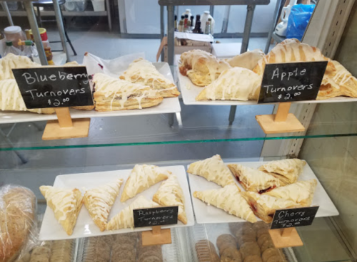 Display case with blueberry, apple, raspberry, and cherry turnovers, each labeled with prices.