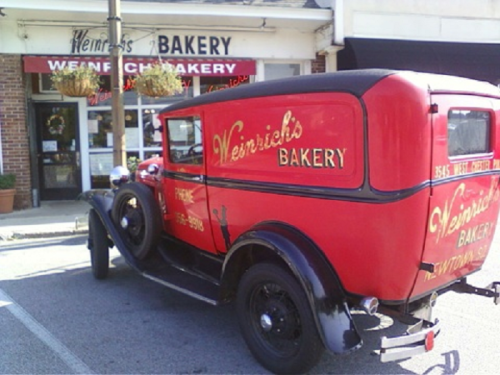 A vintage red bakery truck parked outside Weirich's Bakery, showcasing classic signage and a charming storefront.