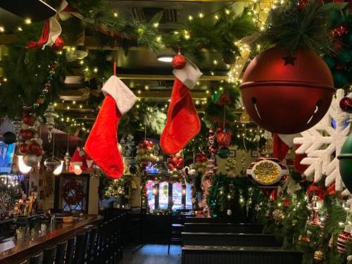 A festive bar decorated with Christmas stockings, ornaments, and twinkling lights, creating a cozy holiday atmosphere.