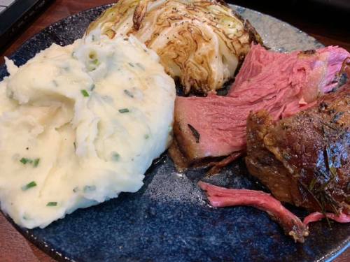 A plate featuring sliced roast beef, creamy mashed potatoes, and grilled cabbage.