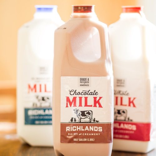 Three milk jugs, one labeled "Chocolate Milk" from Richlands Dairy, with two other jugs in the background.
