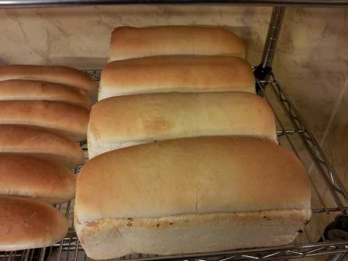 Freshly baked loaves of bread cooling on a wire rack, golden brown and evenly shaped.