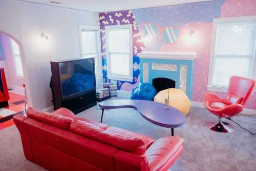 A colorful living room with a red couch, bean bags, a unique coffee table, and vibrant wall patterns.