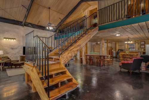 Interior of a rustic home featuring a wooden staircase, open space, and a cozy living area with dining furniture.