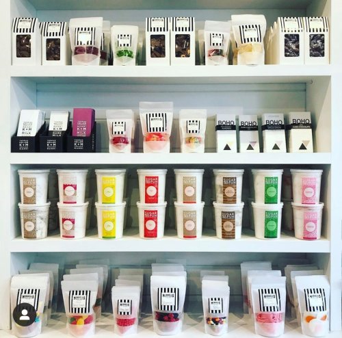 A neatly organized shelf displaying various colorful candy and snack packages in clear containers.