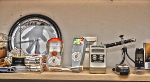 A collection of various electronic devices and tools displayed on a shelf, including meters and a radio antenna.