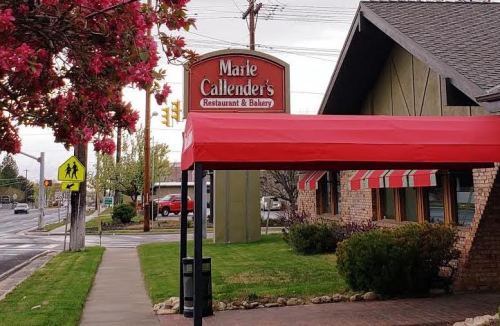 Exterior of Marie Callender's Restaurant & Bakery, featuring a red awning and blooming flowers nearby.