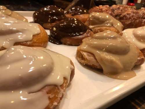 A platter of assorted donuts topped with creamy glazes in chocolate and vanilla flavors.
