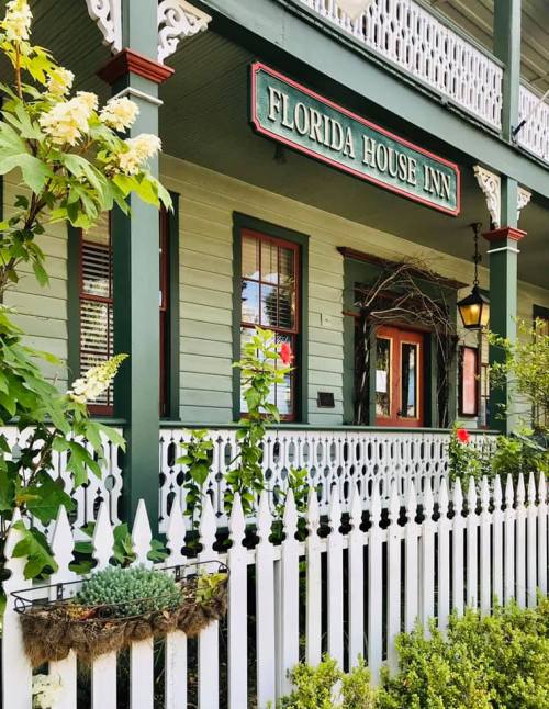 Charming exterior of the Florida House Inn, featuring green walls, white trim, and a welcoming porch with flowers.