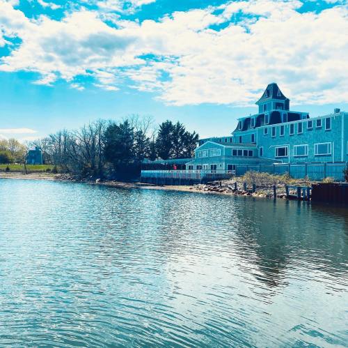 A serene waterfront view featuring a blue building and trees under a bright sky with scattered clouds.