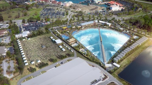 Aerial view of a large water park featuring a wave pool, surrounded by greenery and parking areas.