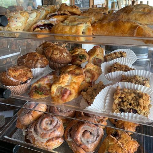 A display case filled with various baked goods, including muffins, pastries, and cinnamon rolls.