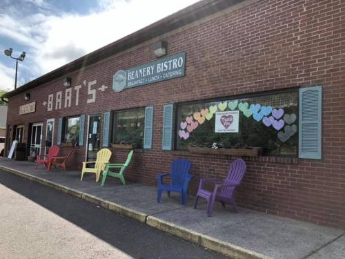 A brick building with colorful chairs outside and heart decorations in the windows, labeled "Beanery Bistro."