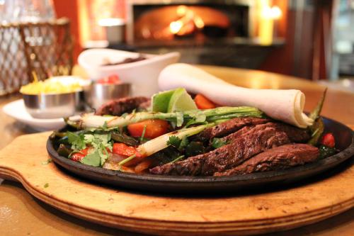 Sizzling steak fajitas with grilled vegetables, served on a hot plate with tortillas in a cozy restaurant setting.
