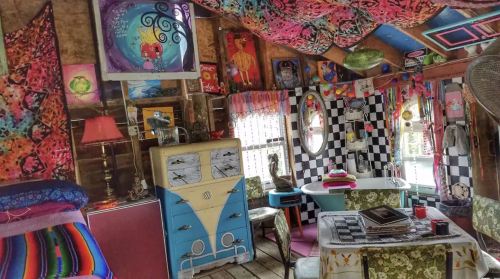 Colorful, eclectic interior of a cozy room with vibrant decor, patterned walls, and unique furniture pieces.