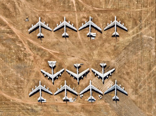Aerial view of multiple aircraft lined up on a dry, barren landscape, showcasing their wings and fuselages.