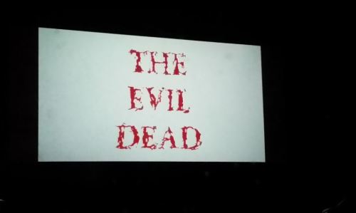 Title card for "The Evil Dead" displayed on a screen, featuring bold red text on a white background.