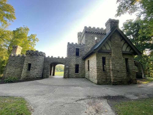 A stone castle with turrets and an archway, surrounded by trees and a clear sky.