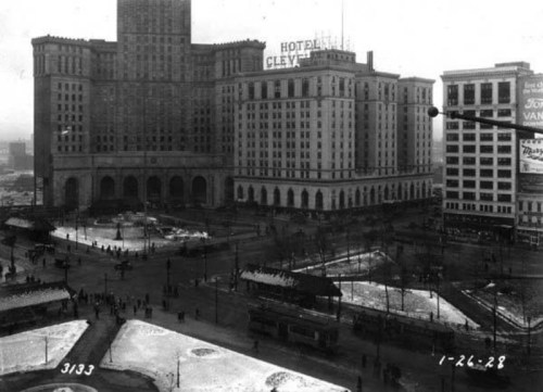 Historic black-and-white photo of a city square with buildings, streetcars, and people, dated January 26, 1928.